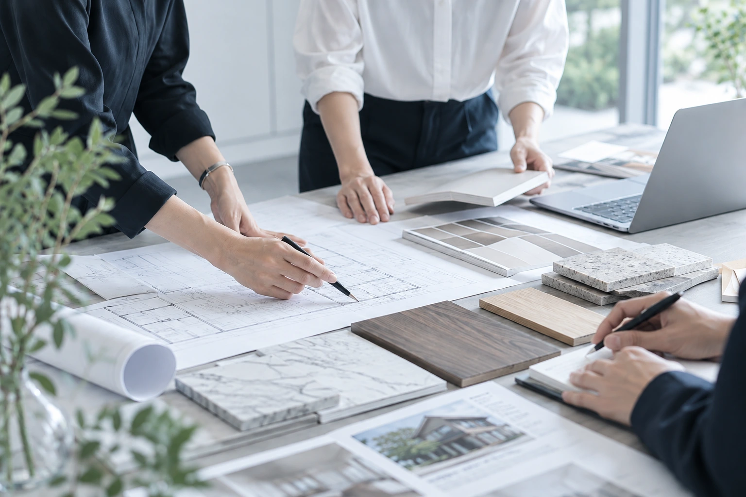図面と建材サンプルを囲んで仕様を検討するスタッフの手元
